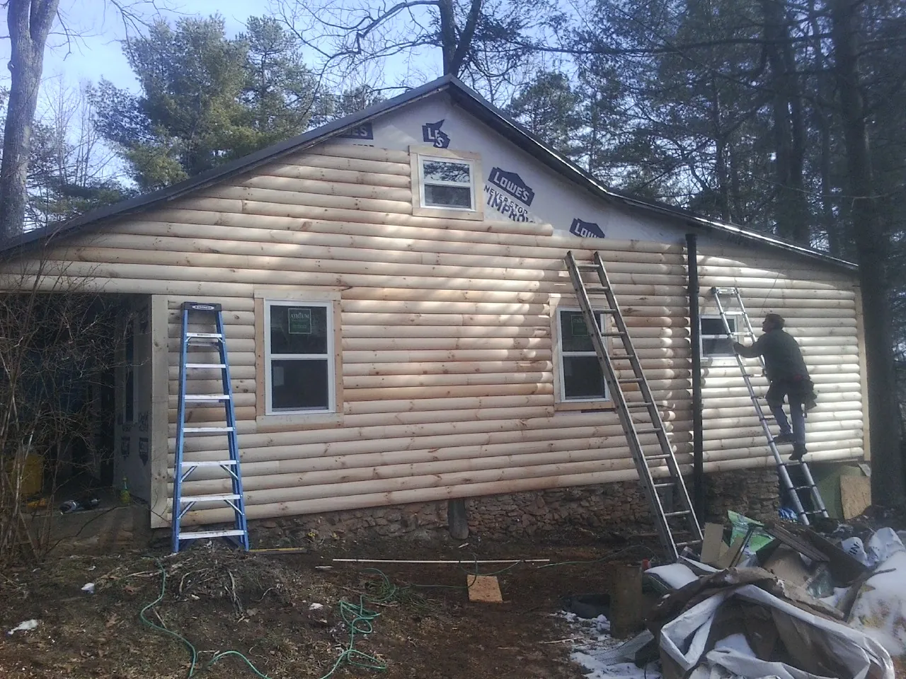 Ladders set against fresh log siding during an exterior remodel in Douglas